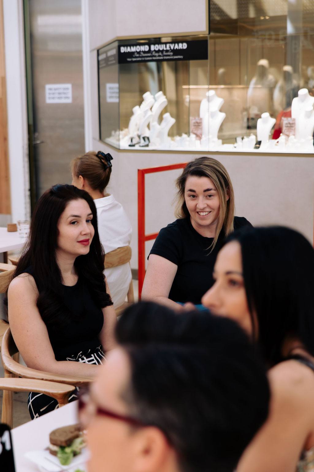Women at a table at an Adelaide event, one glancing across the room