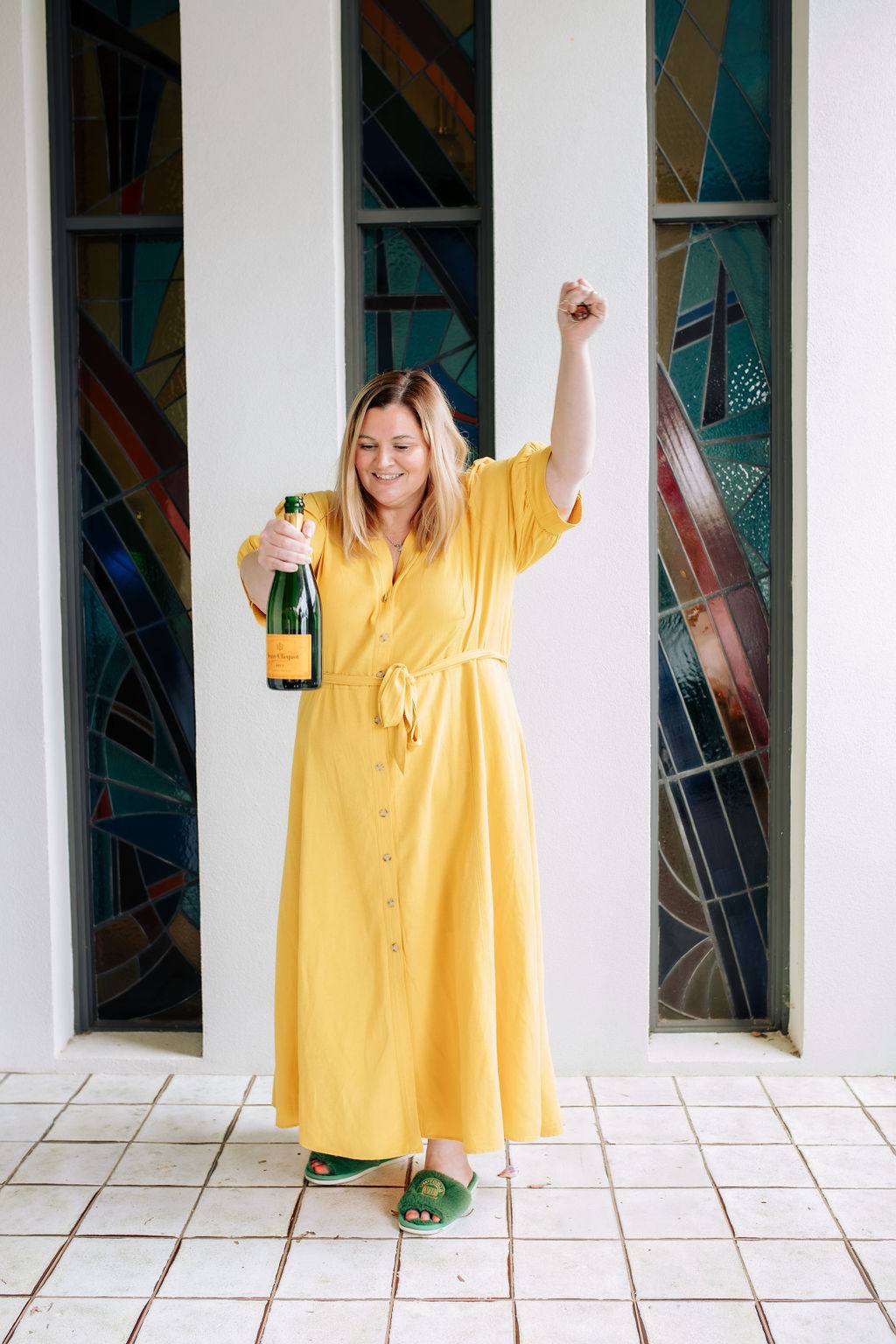 Woman in a yellow dress dancing with a bottle of champagne
