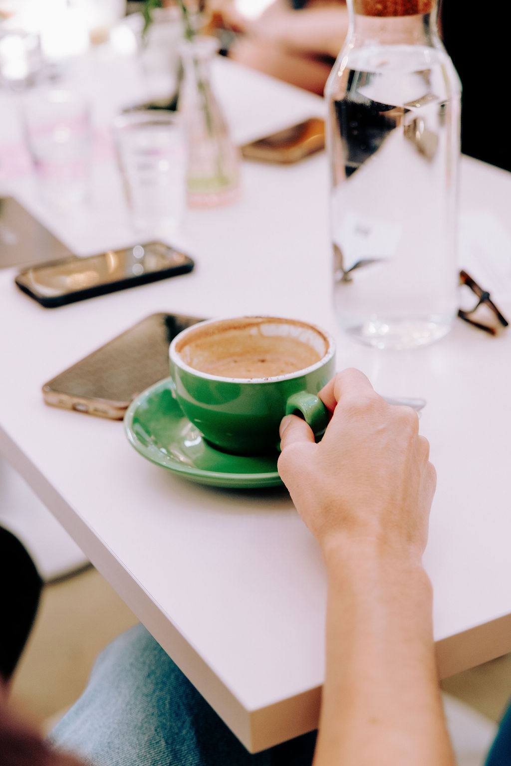 A hand wrapped around a bright green espresso cup