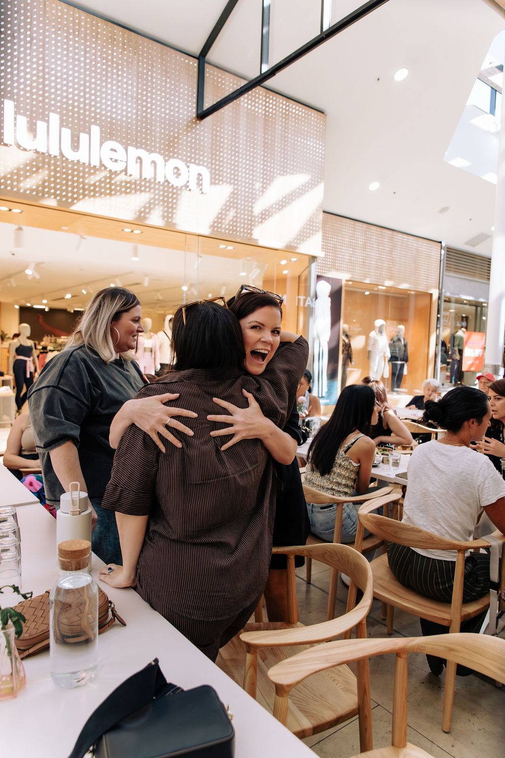 Sandra holding a woman in a tight hug while a friend looks on smiling